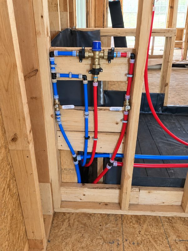 Shower mixing valve roughed in with red and blue PEX lines